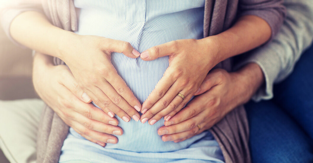 Gravid kvinna håller på sin mage
