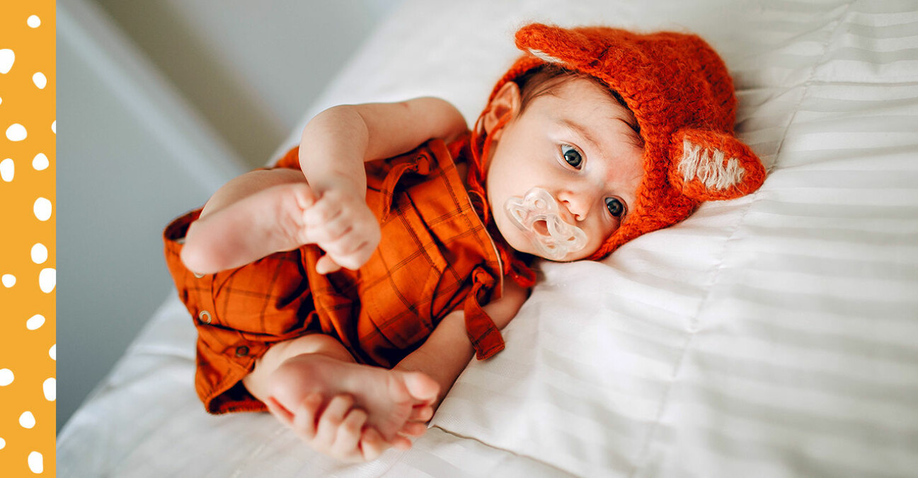 Bebis i gullig orange dräkt med öron.