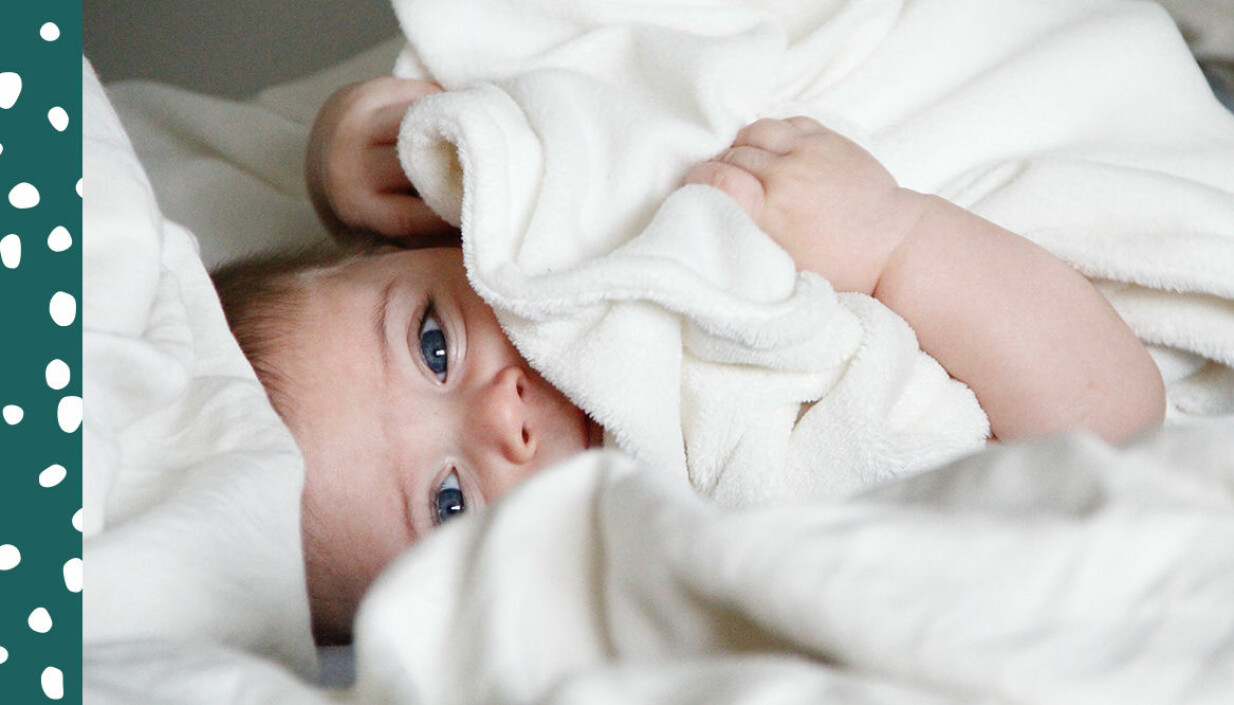 Bebis gömmer sig under mysig vit filt.