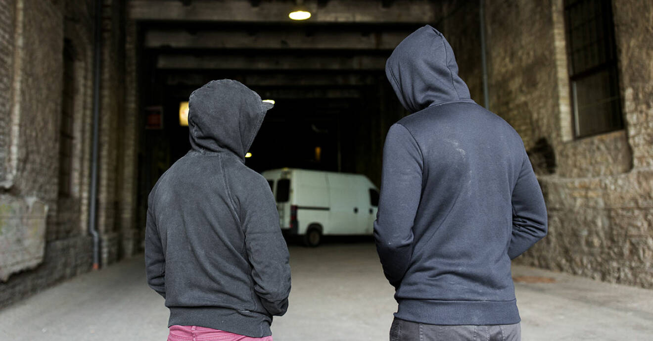 Två unga killar i hoodies står i mörk gång med en skåpbil som skymtar i bakgkrunden.