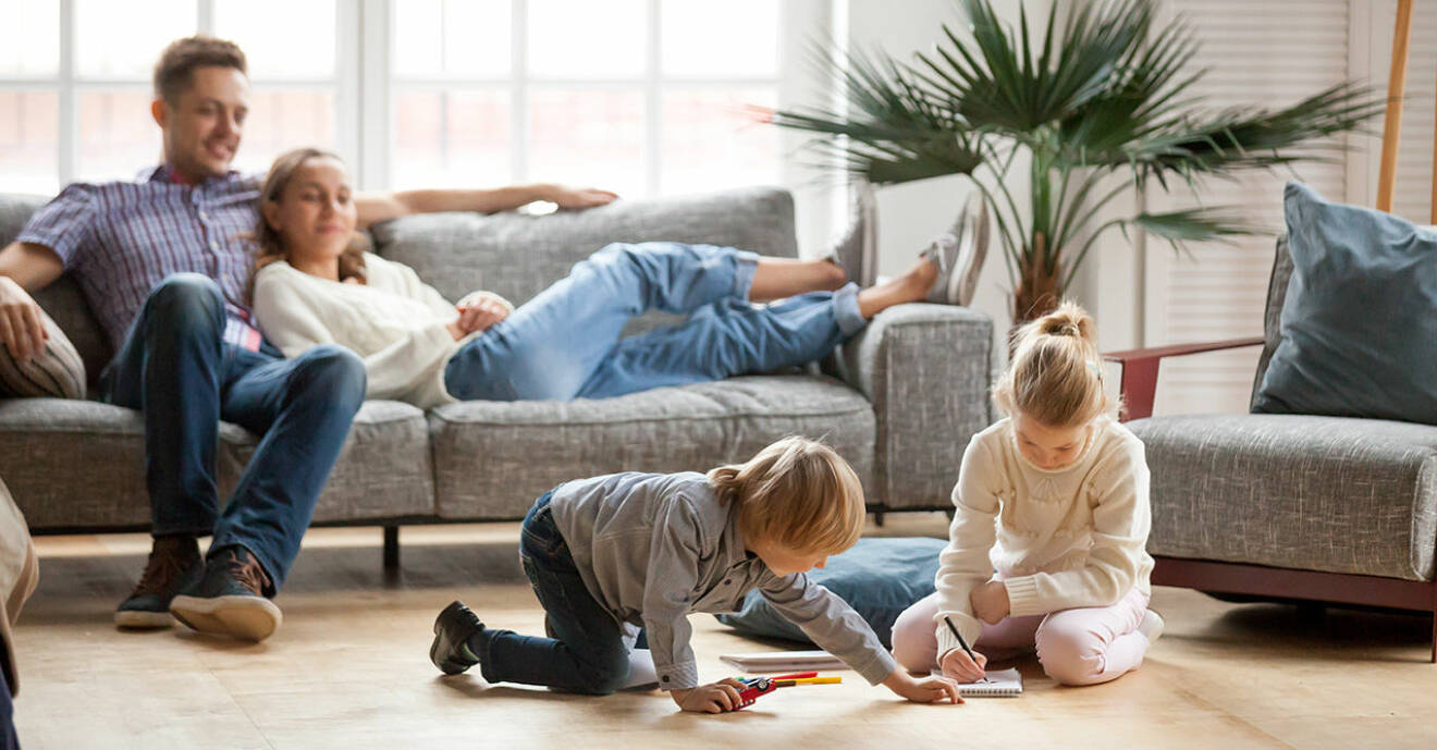 Familj i soffa med lekande barn på golvet