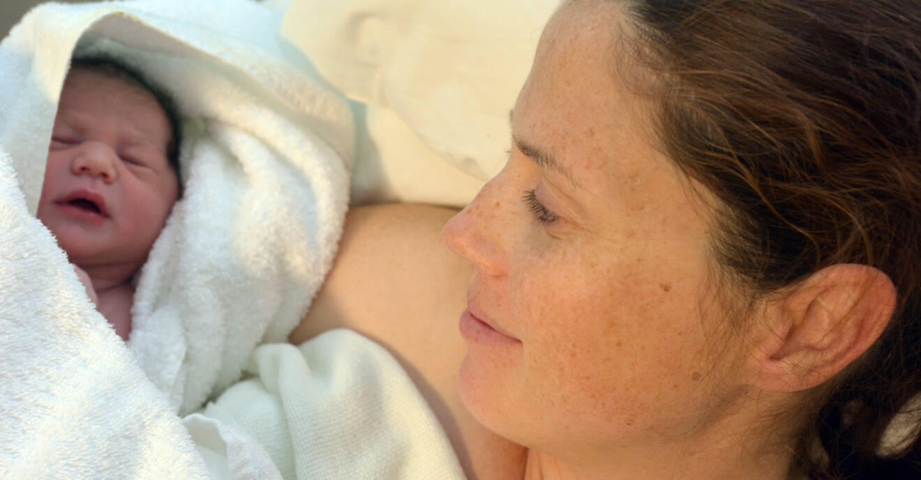 Kvinna som ligger med nyfödd bebis i famnen.