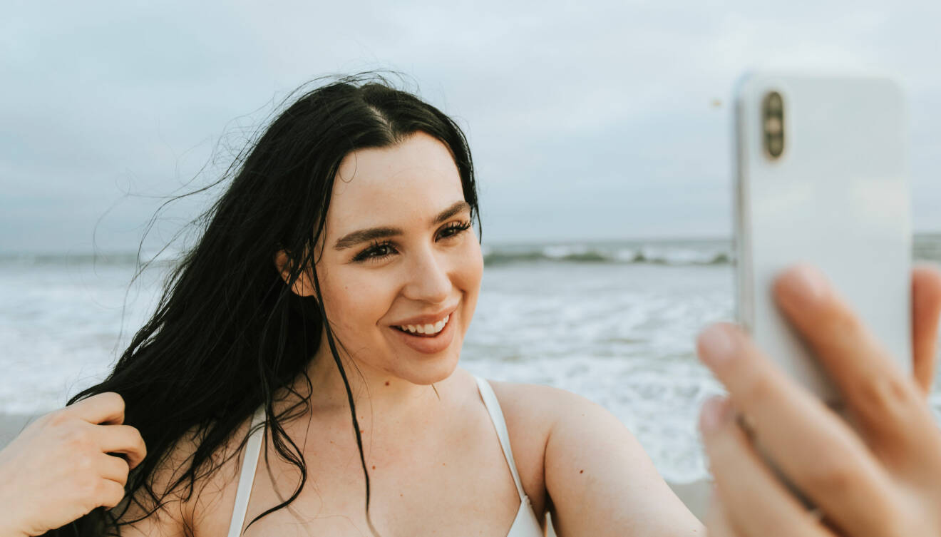Kvinna är på stranden och tar selfie