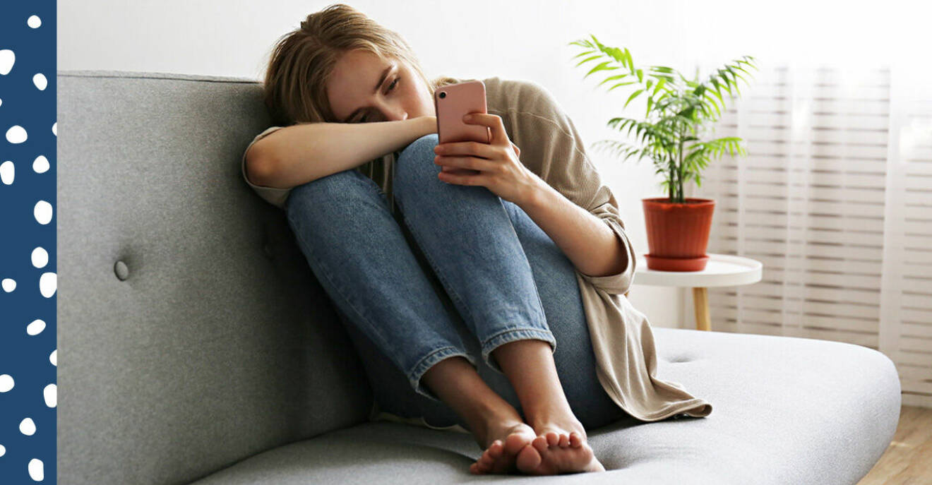 Ung kvinna med mobil i en soffa