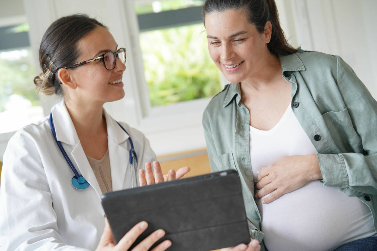 Gravid kvinna pratar med barnmorska