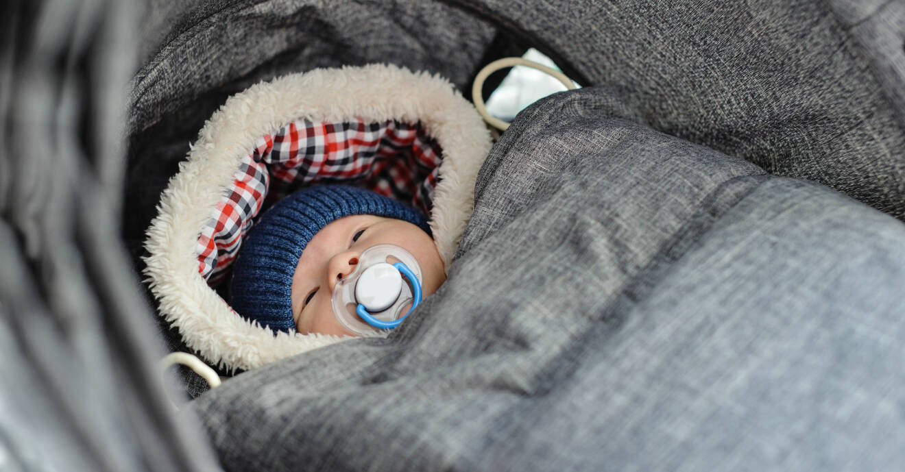 Bebis som är klädd för vintern i åkpåse