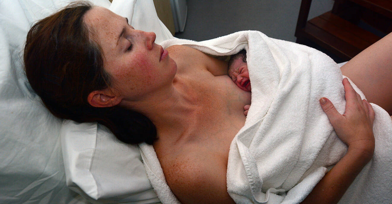 Kvinna med nyfödd bebis efter förlossningen