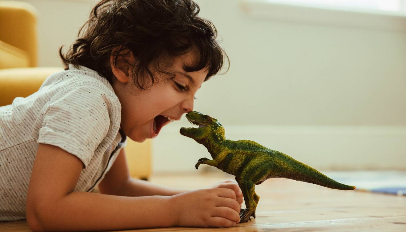 barn leker med dinosaurie