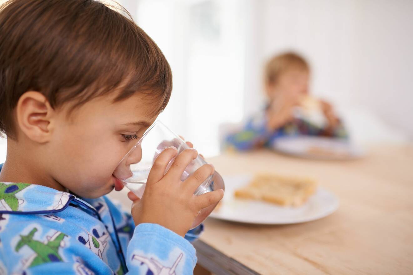 pojke dricker vatten vid frukostbordet