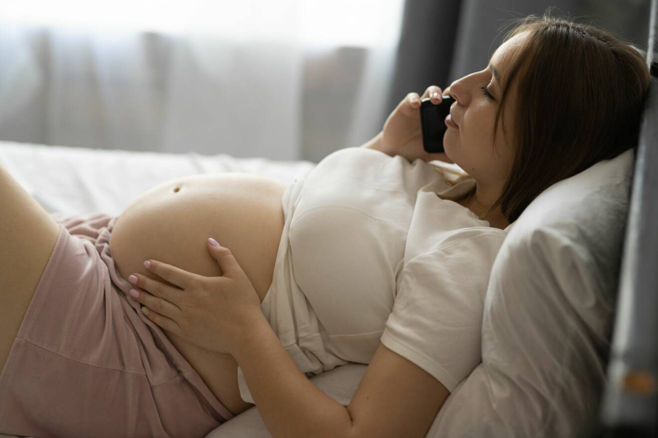 gravid kvinna talar i telefon