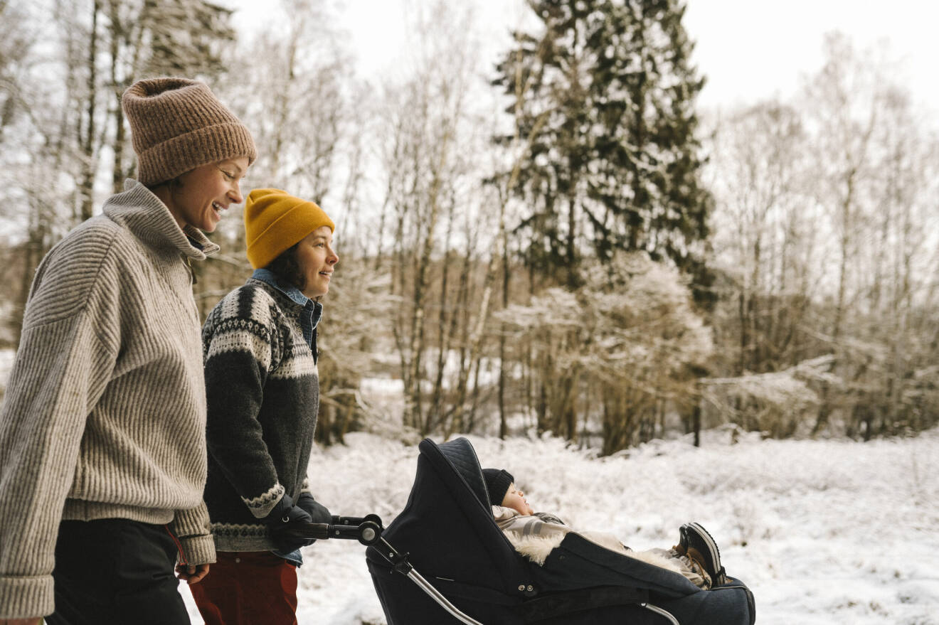 glatt par promenerar med barnvagn i snö