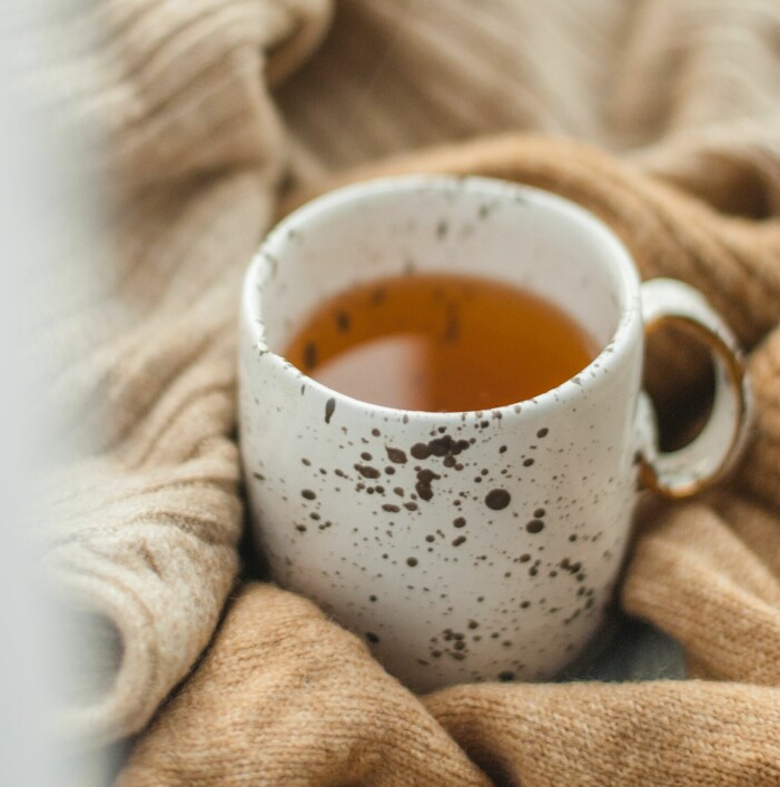 En vit kopp med prickar med te i.