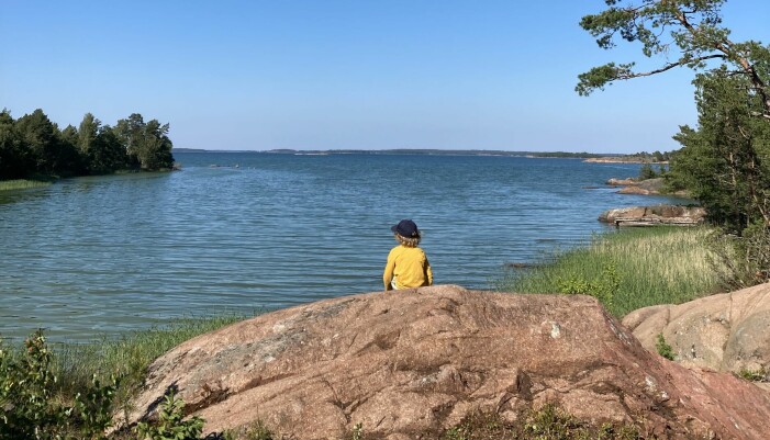 Att sätta sig på en röd granitklippa och spana efter sjöfåglar eller andra djur är bra sysselsättning, tycker Knut, 8 år. Foto: Privat Knut sitter på åländsk granitklippa och tittar på havet