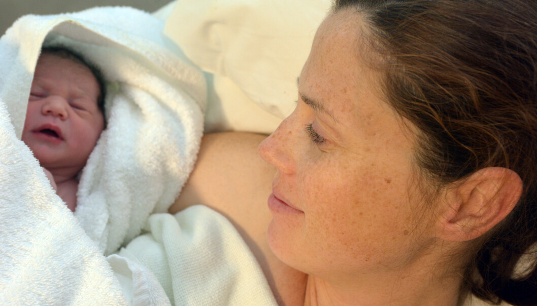 Kvinna som ligger med nyfödd bebis i famnen.