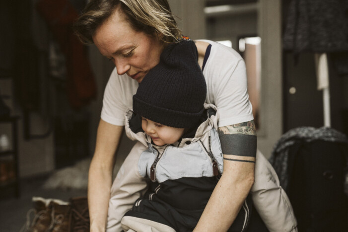 Mamma klär på dotter sittande i hall hemma mamma klär på barn