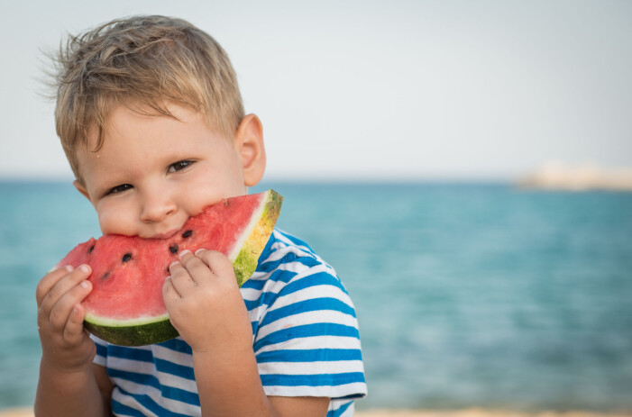 Vattenmelon är en klassiker på stranden. Mums! pojke äter vattenmelon