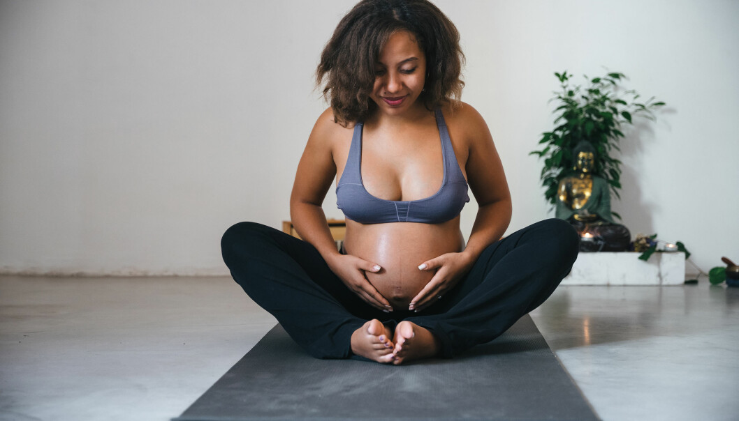 Ett lugnt, skönt yogapass är toppen för både kropp och knopp. Gravid kvinna yogar inomhus
