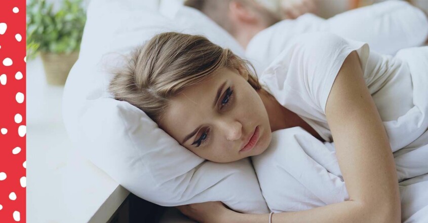 Kvinna ser ledsen ut liggandes i en säng