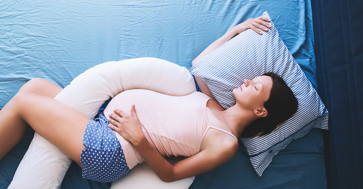 En amningskudde är perfekt att sova med för att avlasta kroppen under graviditeten. gravid kvinna som sover