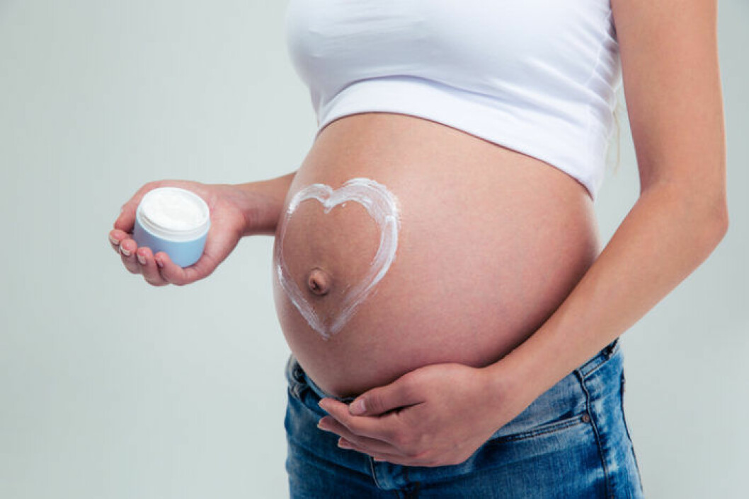 gravid kvinna smörjer ett hjärta på magen