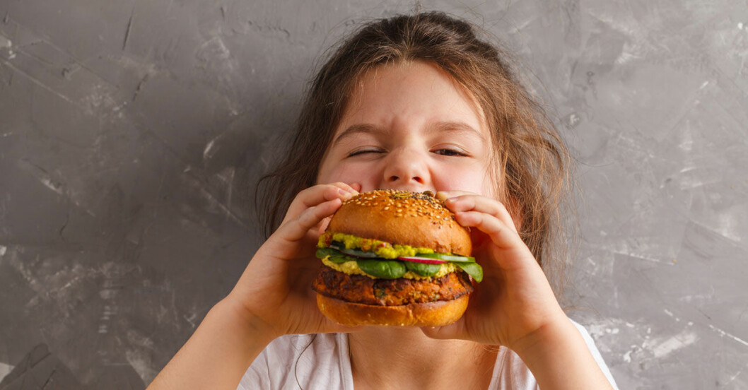 Barn tar bett av vegetarisk hamburgare.
